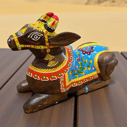 Decorative wooden bull figurine with colorful paint on a wooden surface