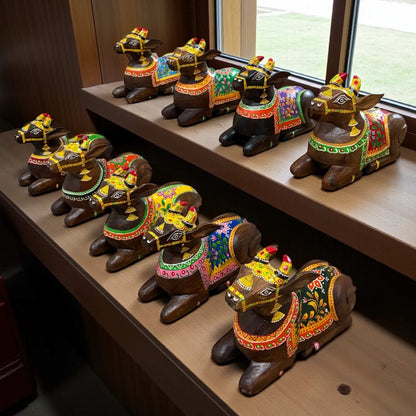 Decorative cow figurines with colorful patterns on a wooden shelf.
