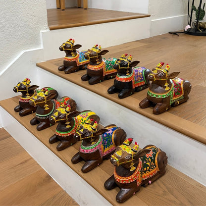 Multiple 9-inch hand-painted mango-wood Nandi figurines in different color variants, displayed together  on a wooden staircase.