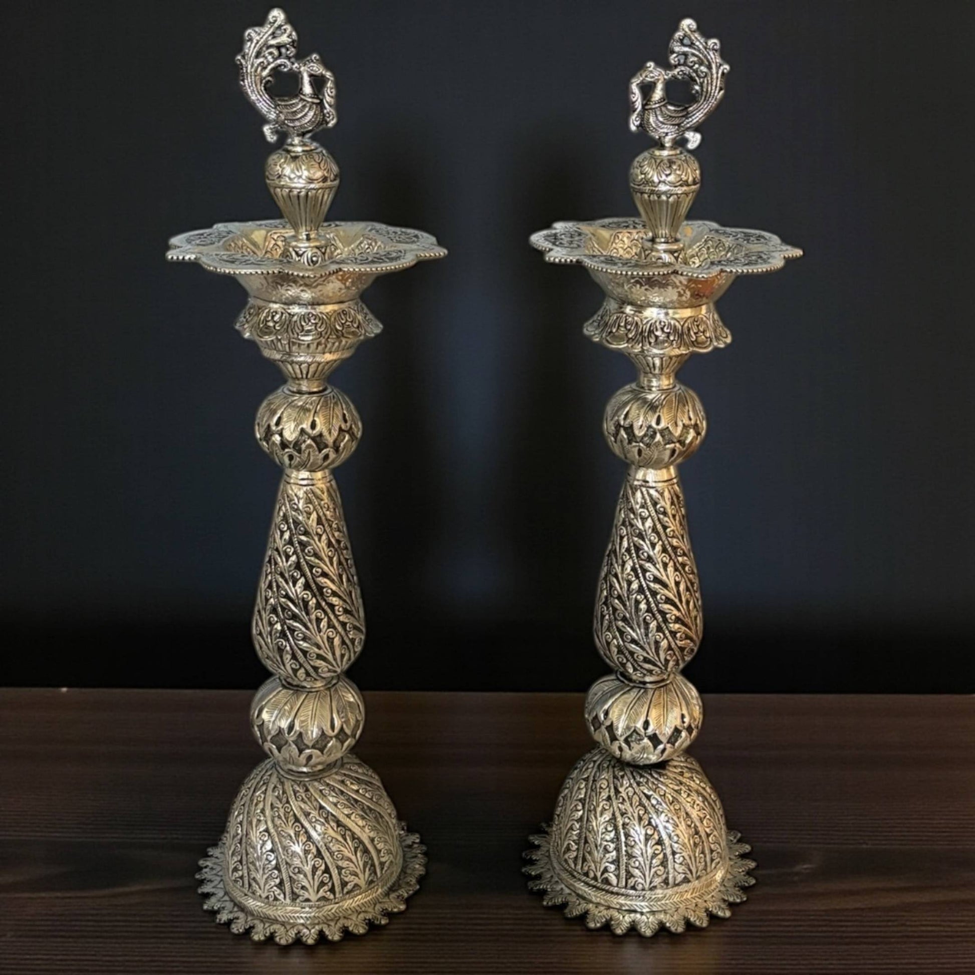 Two ornate silver candle holders on a dark background