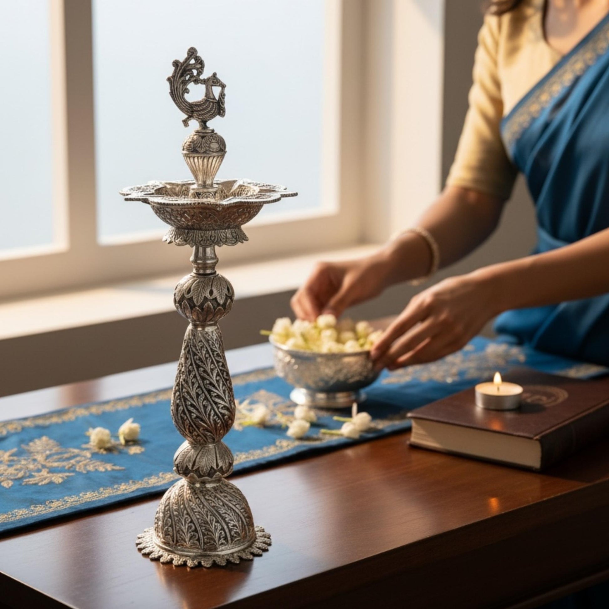 Decorative silver oil lamp by urli utsav decor  on a table with a person preparing offerings.