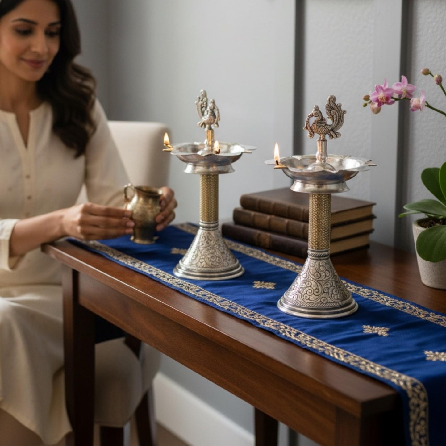Woman lighting traditional peacock samai oil lamps on table decor setting