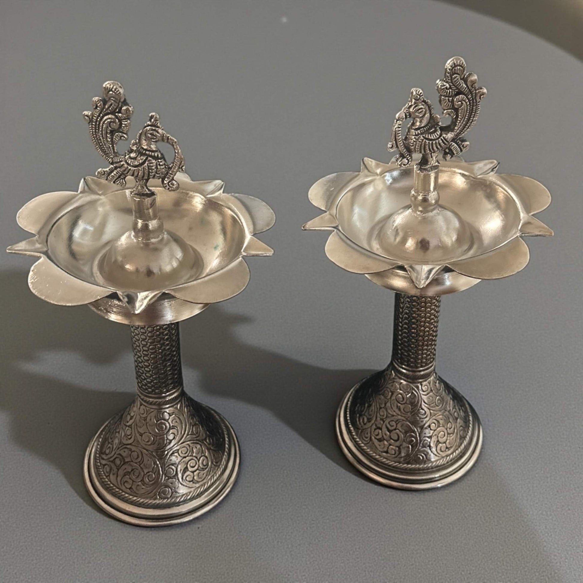 Pair of ornate silver samai oil lamps on gray backdrop