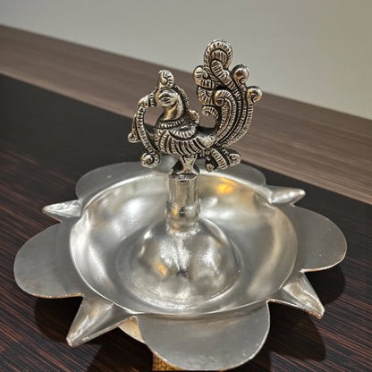 Close-up of intricate engraved silver peacock samai oil lamp design
