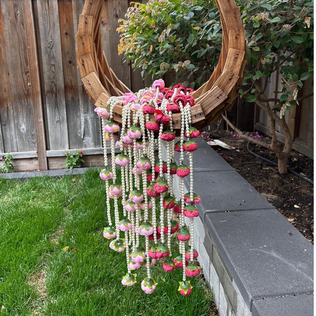 Decorative hanging plant holder with pink and white flowers in a garden setting.