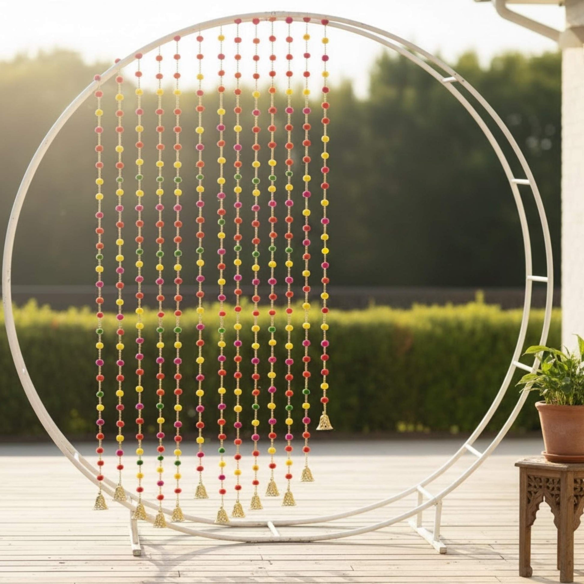 Multicolor pompom garland draped on circular metal frame, outdoor deck decor