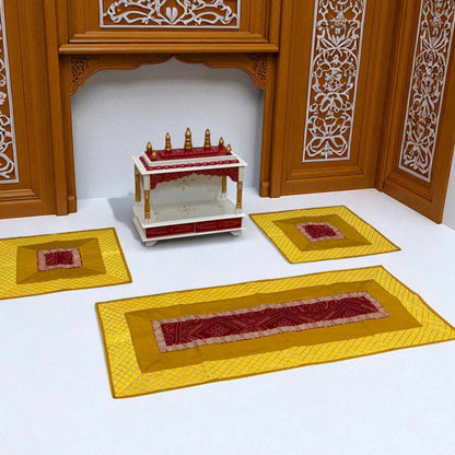 Decorative setup with a small table and three yellow mats with red patterns on a white background.