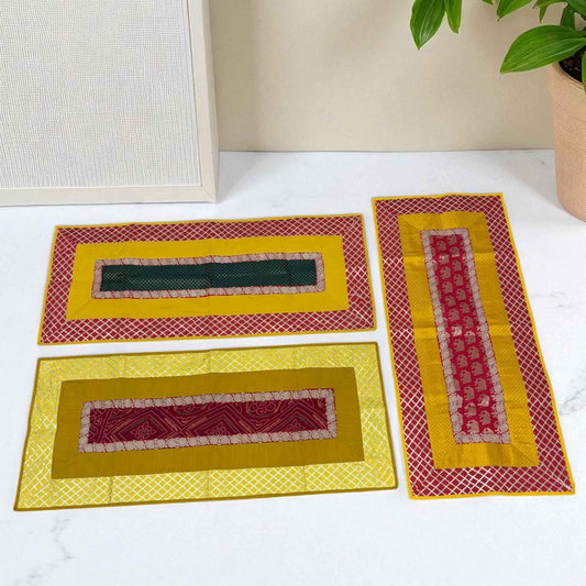 Puja Aasan Mat in three design choices – Emerald Lattice with green center and red lattice border, Golden Maroon Classic with maroon patterned center and yellow lattice border, and Elephant Regal with maroon elephant motif and red lattice border.