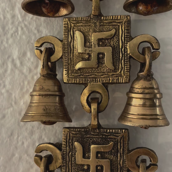 video of A handcrafted 15-inch brass Swastik wall hanging featuring intricate engravings and a polished gold finish, symbolizing prosperity and positive energy