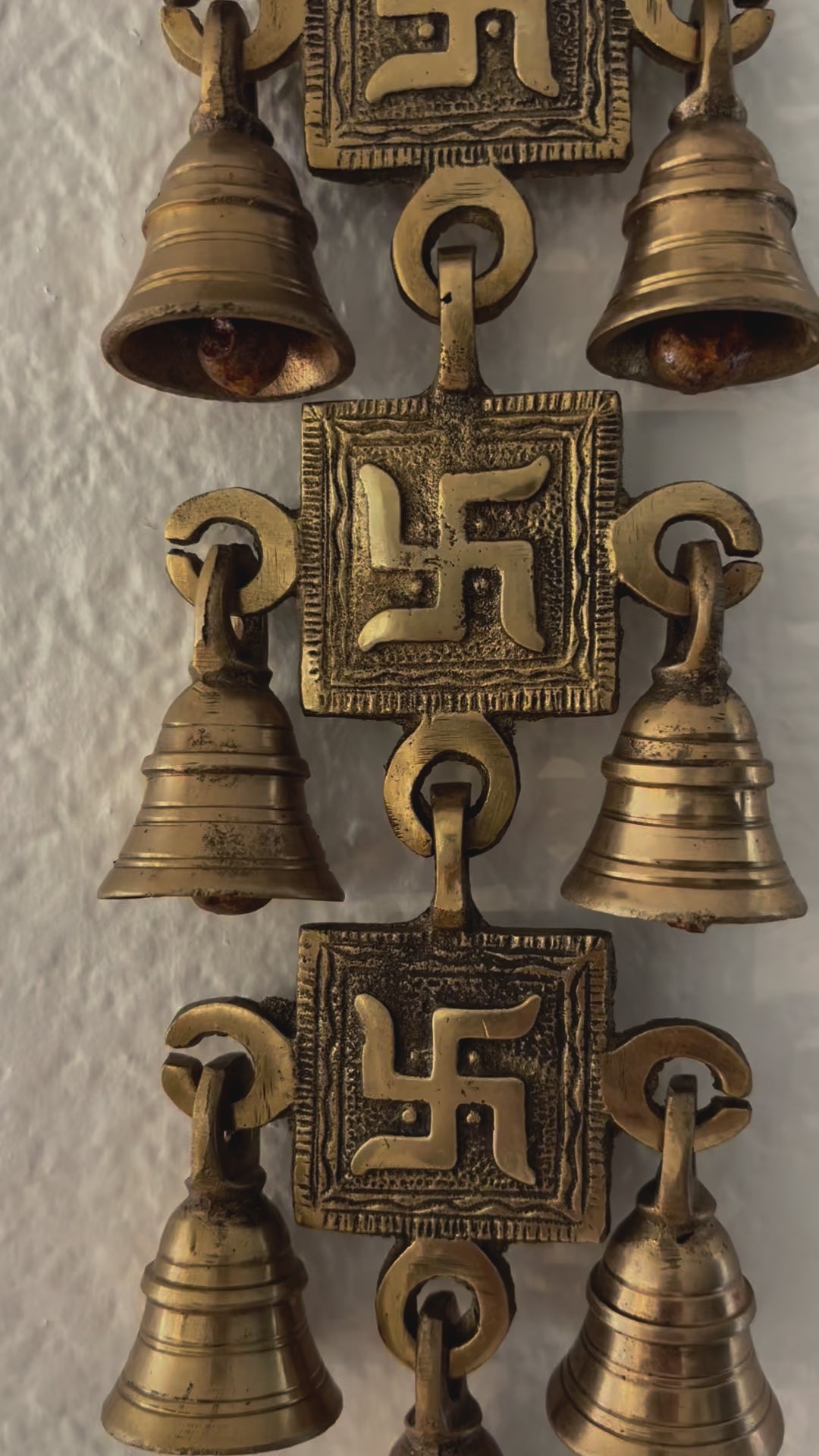 video of A handcrafted 15-inch brass Swastik wall hanging featuring intricate engravings and a polished gold finish, symbolizing prosperity and positive energy