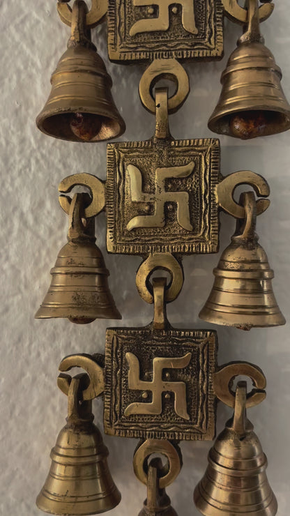 video of A handcrafted 15-inch brass Swastik wall hanging featuring intricate engravings and a polished gold finish, symbolizing prosperity and positive energy