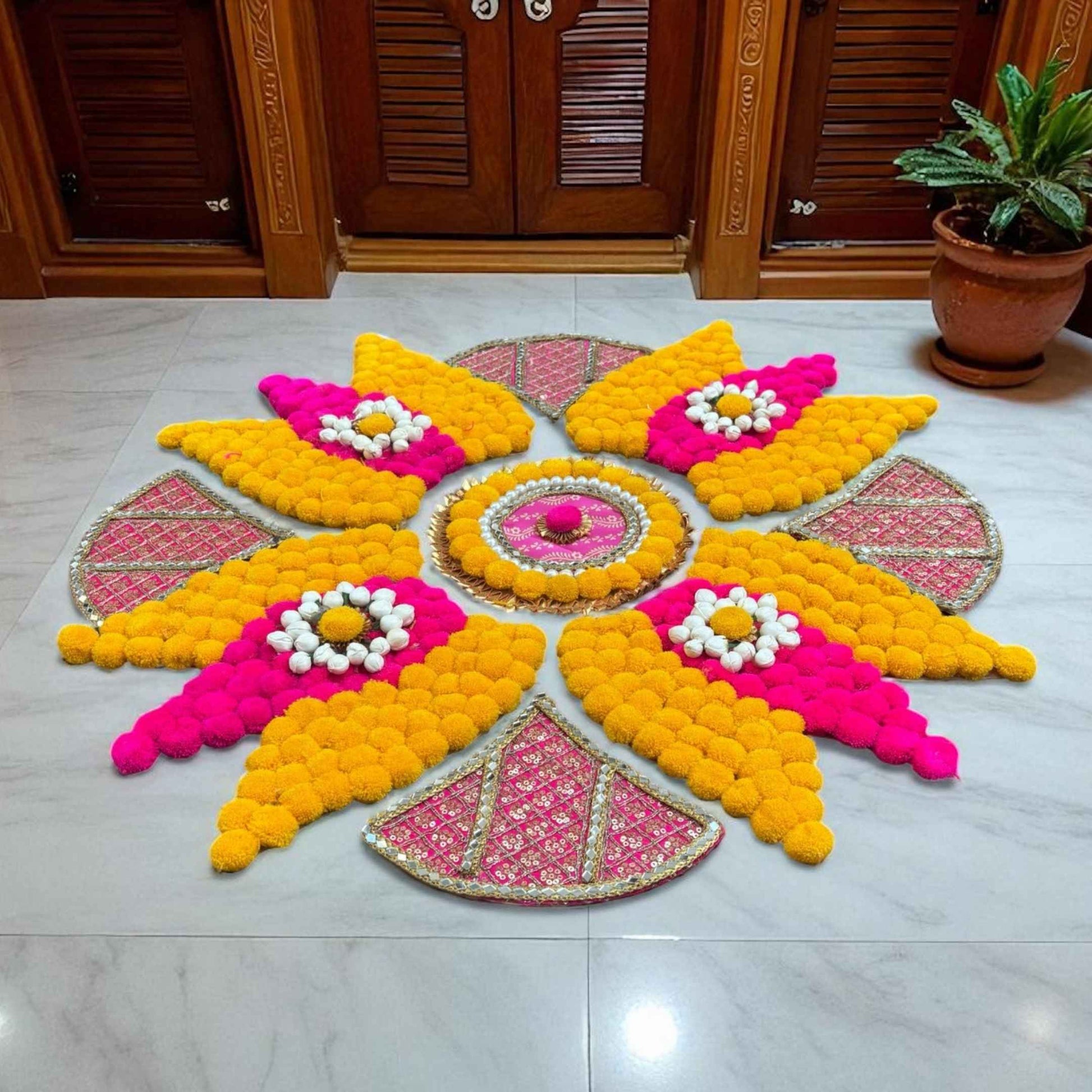 Colorful rangoli mat arrangement on a tiled floor in front of a wooden door.