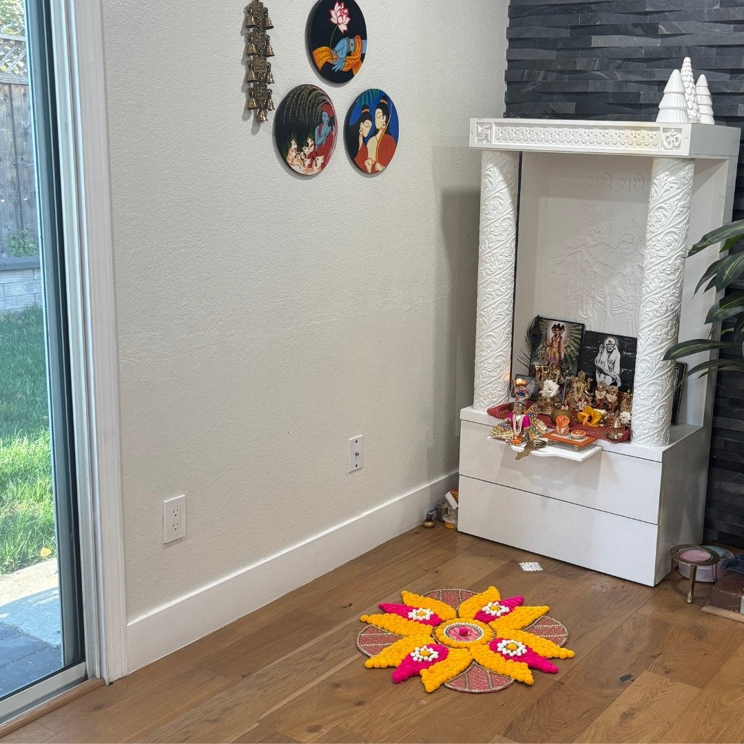 Home altar with decorative items and a colorful rangoli on the floor.