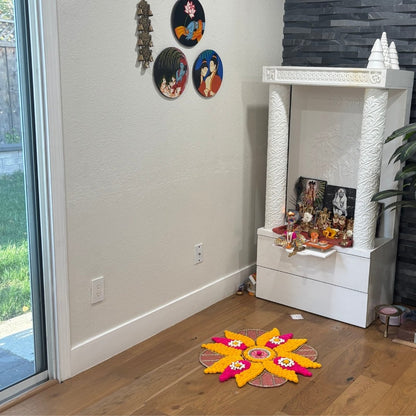 Home altar with decorative items and a colorful rangoli on the floor.