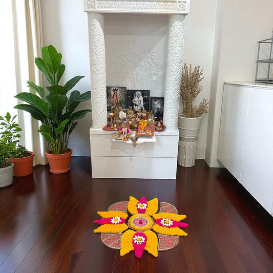 Pooja room with a white altar, plants, and a colorful rangoli mat trishul design on the floor.
