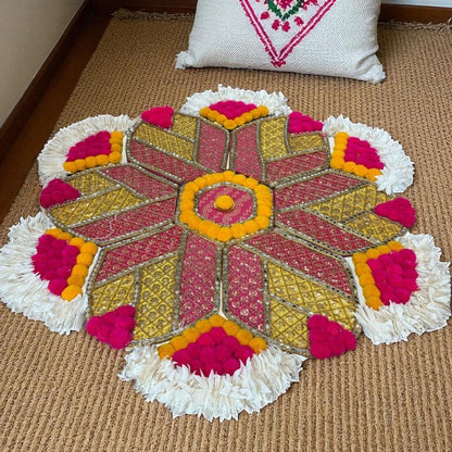Colorful rangoli mat a brown floor with a decorative pillow in the background