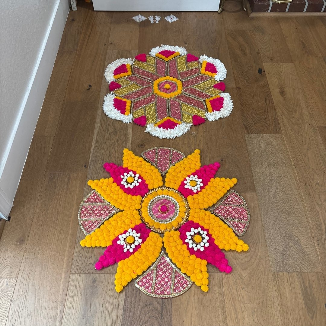 Two colorful MDF rangoli designs arrangements on a wooden floor.