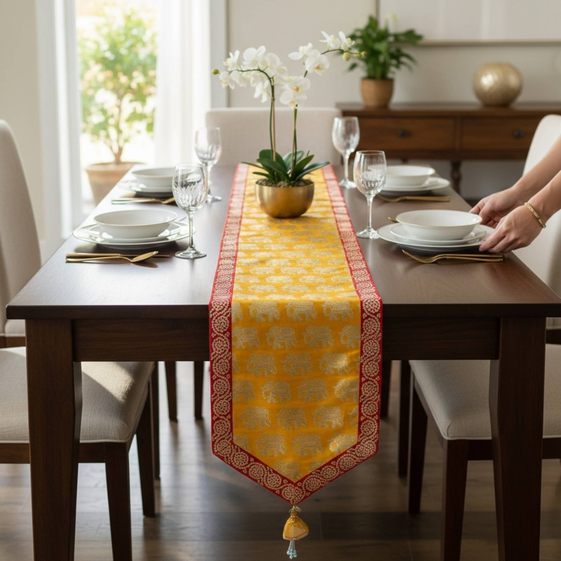 Dining table set with a yellow table runner featuring elephant patterns, in a bright room.
