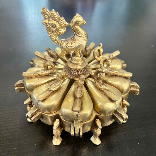 Brass Peacock Shingardani kumkum box, antique gold 9-compartment, closed view on dark wood