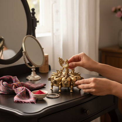 Brass peacock Shingardani sindoor box closed on dark wooden vanity, antique gold finish
