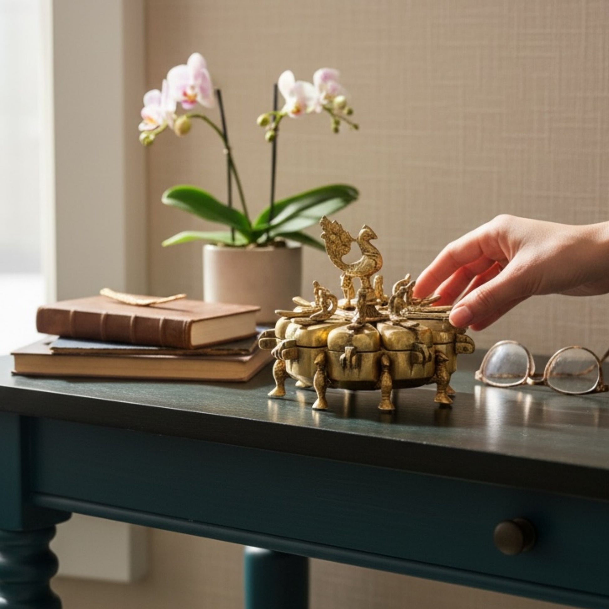 Handmade brass peacock Shingardani on teal table, lifestyle vignette with orchid and books