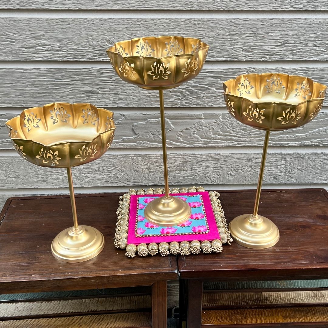 Gold Lotus Motif Urli Set of 3 by Urli Utsav Decor — standing decorative bowls styled on wooden table with decorative pink mat; perfect Diwali centerpiece.