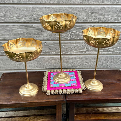 Gold Lotus Motif Urli Set of 3 by Urli Utsav Decor — standing decorative bowls styled on wooden table with decorative pink mat; perfect Diwali centerpiece.