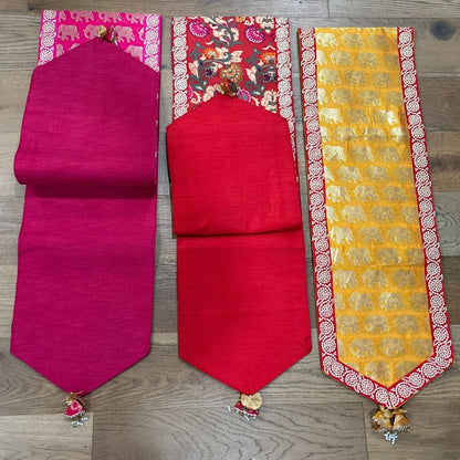 Three colorful table runners on a wooden surface