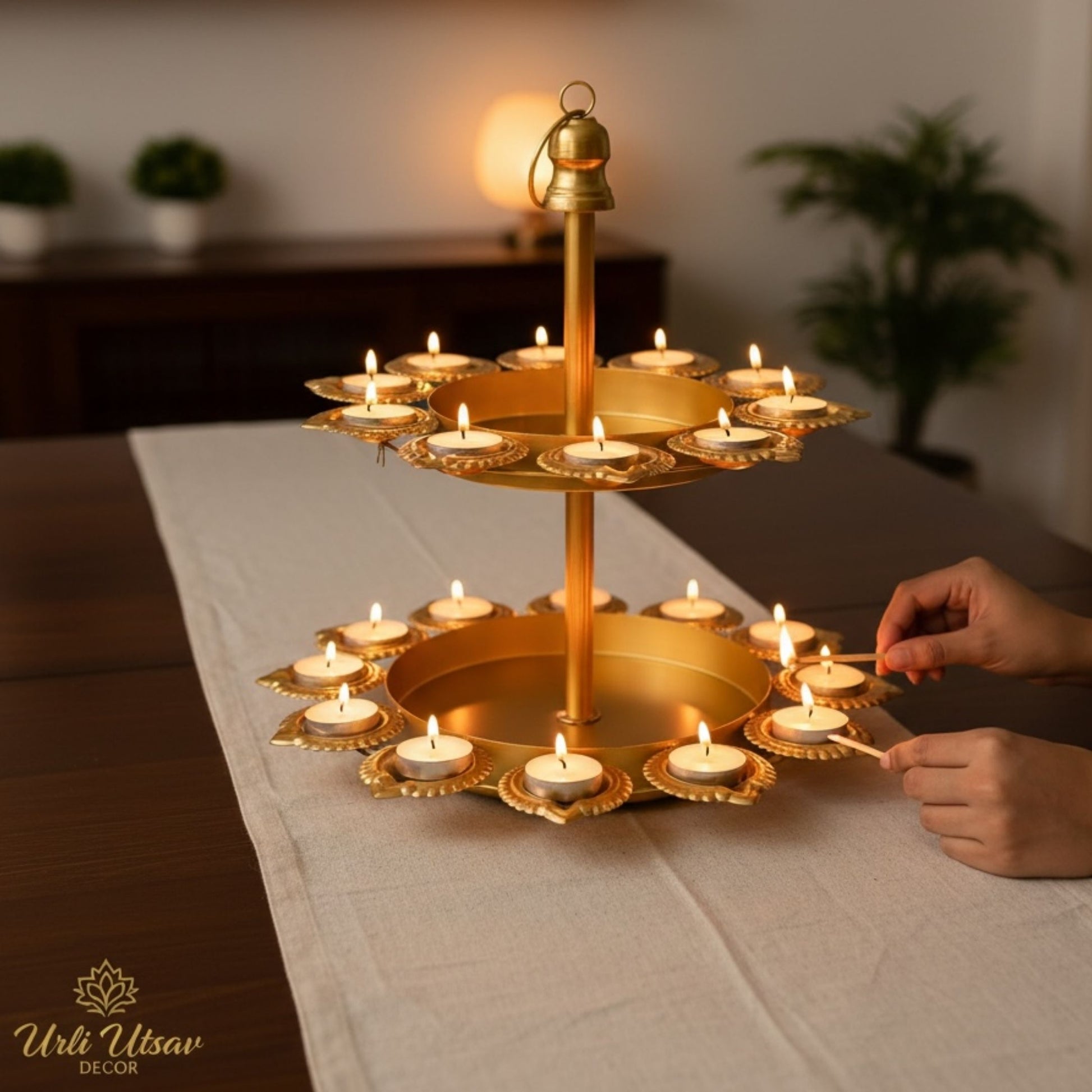 Diwali Decoration setup with two tiered diya stand and floral arrangements on a wooden table, outdoors.