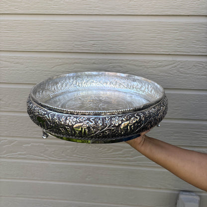 Hand holding the 13.5-inch antique silver urli bowl to show its size, with raised elephants around the wall