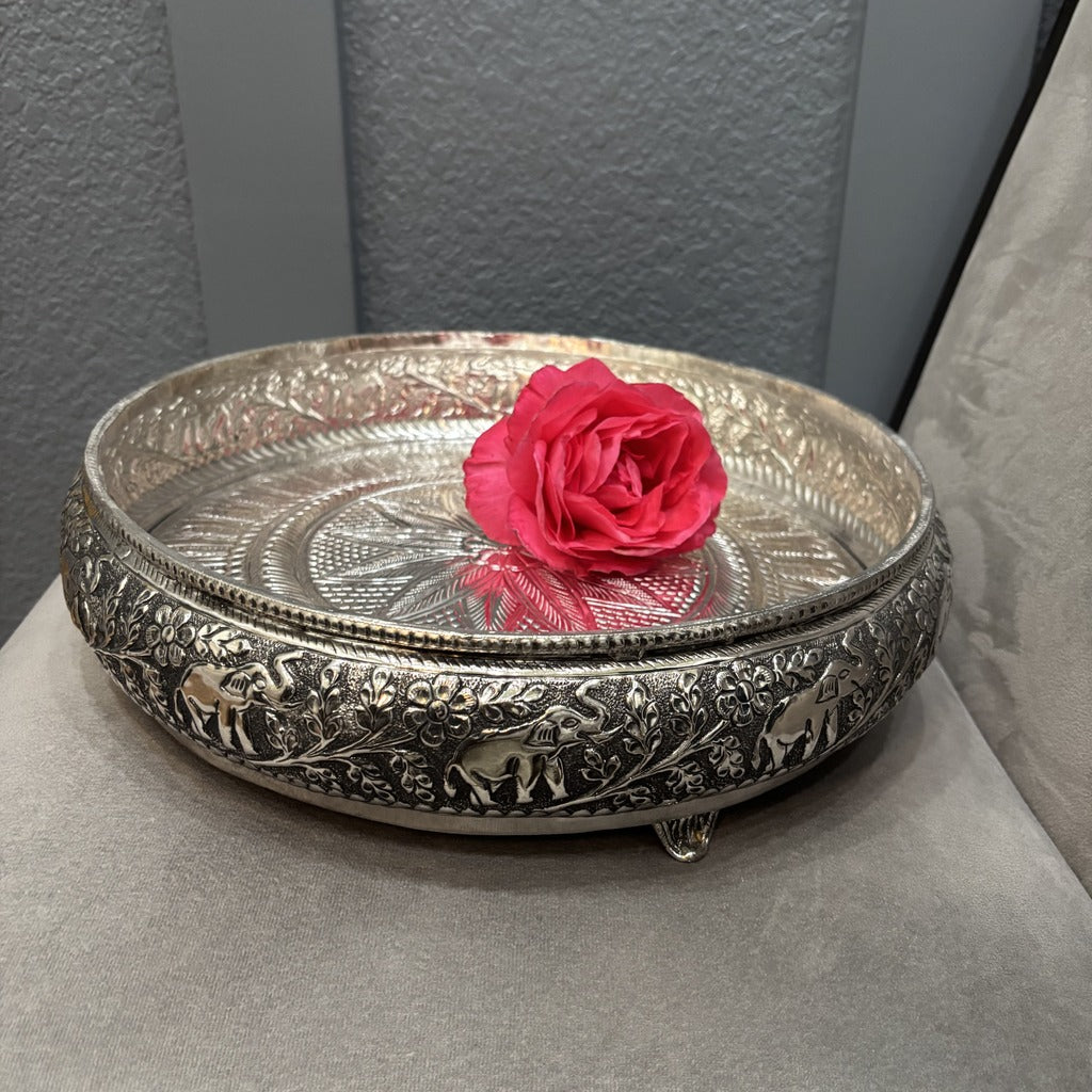 Antique silver urli bowl with a pink rose, showing the patterned inner base and raised elephant border