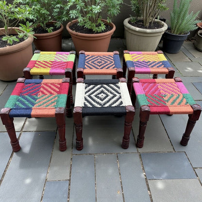 Set of colorful woven stools on a tiled patio with potted plants in the background.