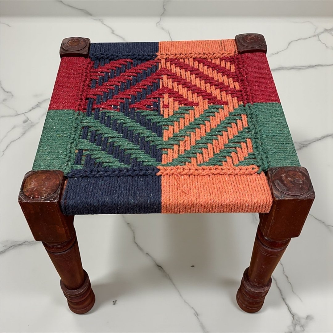 Small woven stool with a geometric pattern on a marble surface