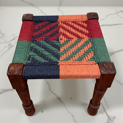 Small woven stool with a geometric pattern on a marble surface