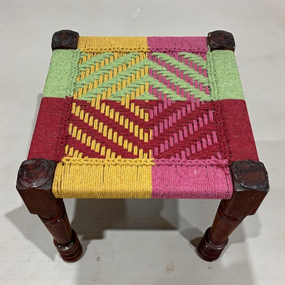 Small woven stool with colorful pattern on a white background