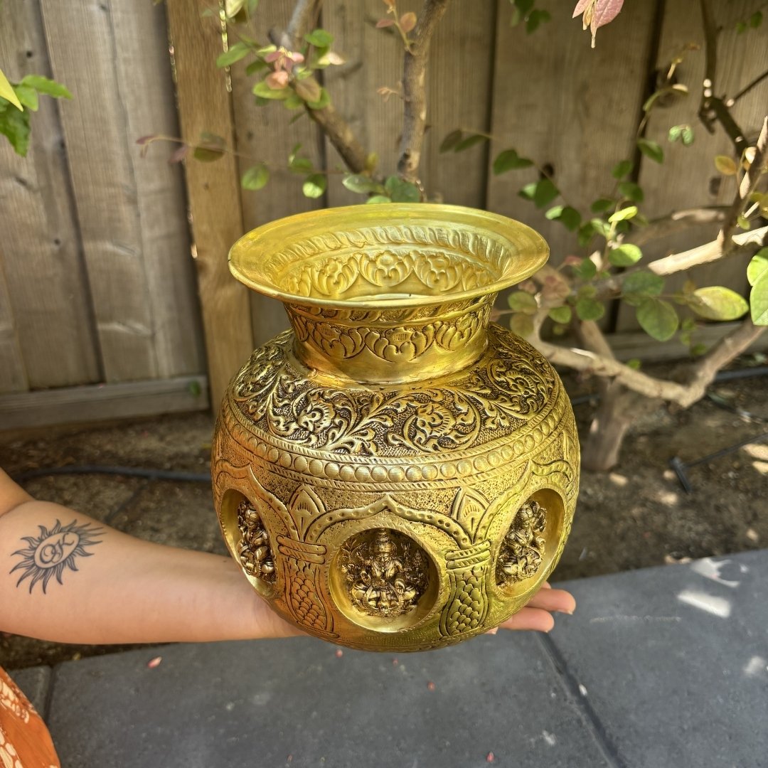 brass kalash with intricate floral engravings and circular cutouts