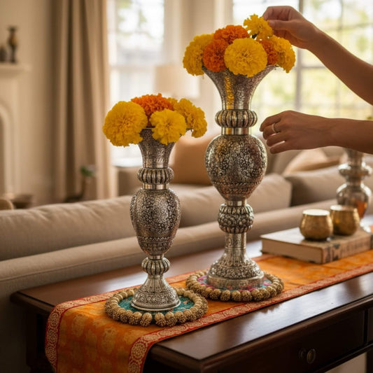 Decorative silver vase holders with marigold flowers on a table in a living room.