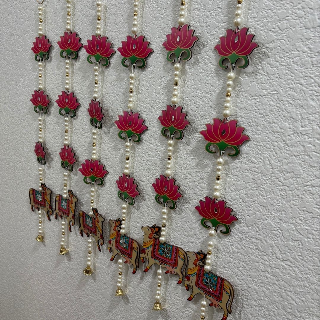 Decorative hanging with pink lotus flowers and colorful deer figures on a white background