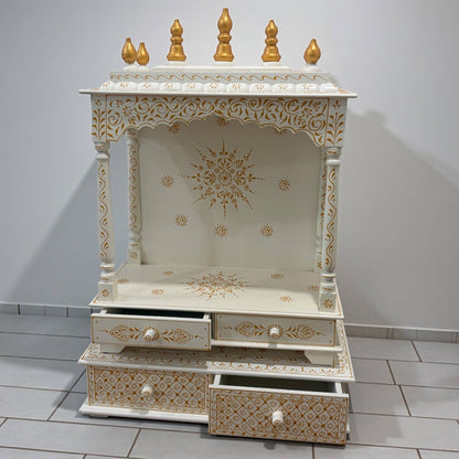 handpainted white and gold mandir with intricate designs on a tiled floor.