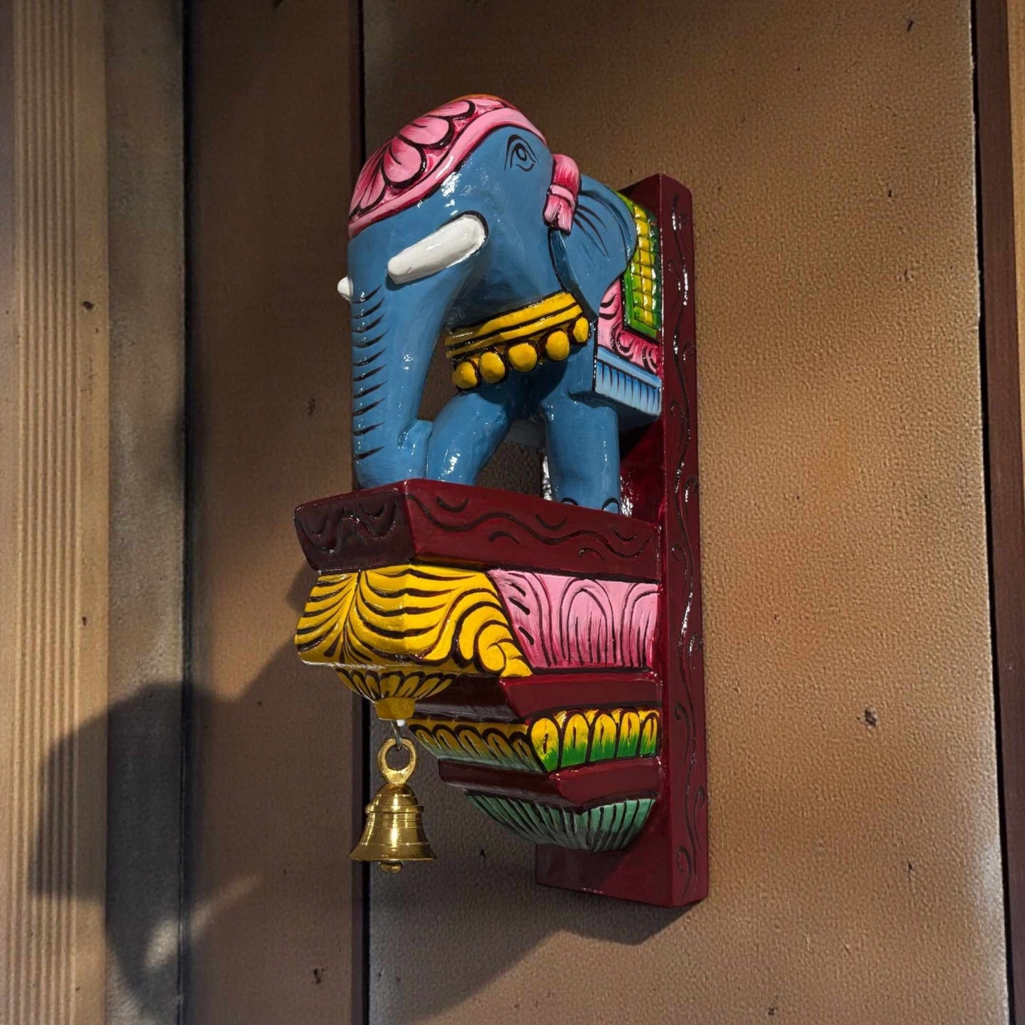 Hand-carved elephant corbel installed as a wall shelf bracket for traditional Indian pooja room decor.