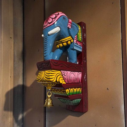Hand-carved elephant corbel installed as a wall shelf bracket for traditional Indian pooja room decor.