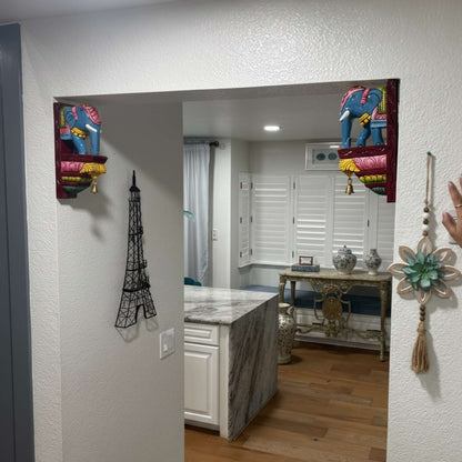 Hand-carved elephant corbel installed as a wall shelf bracket for traditional Indian pooja room decor.