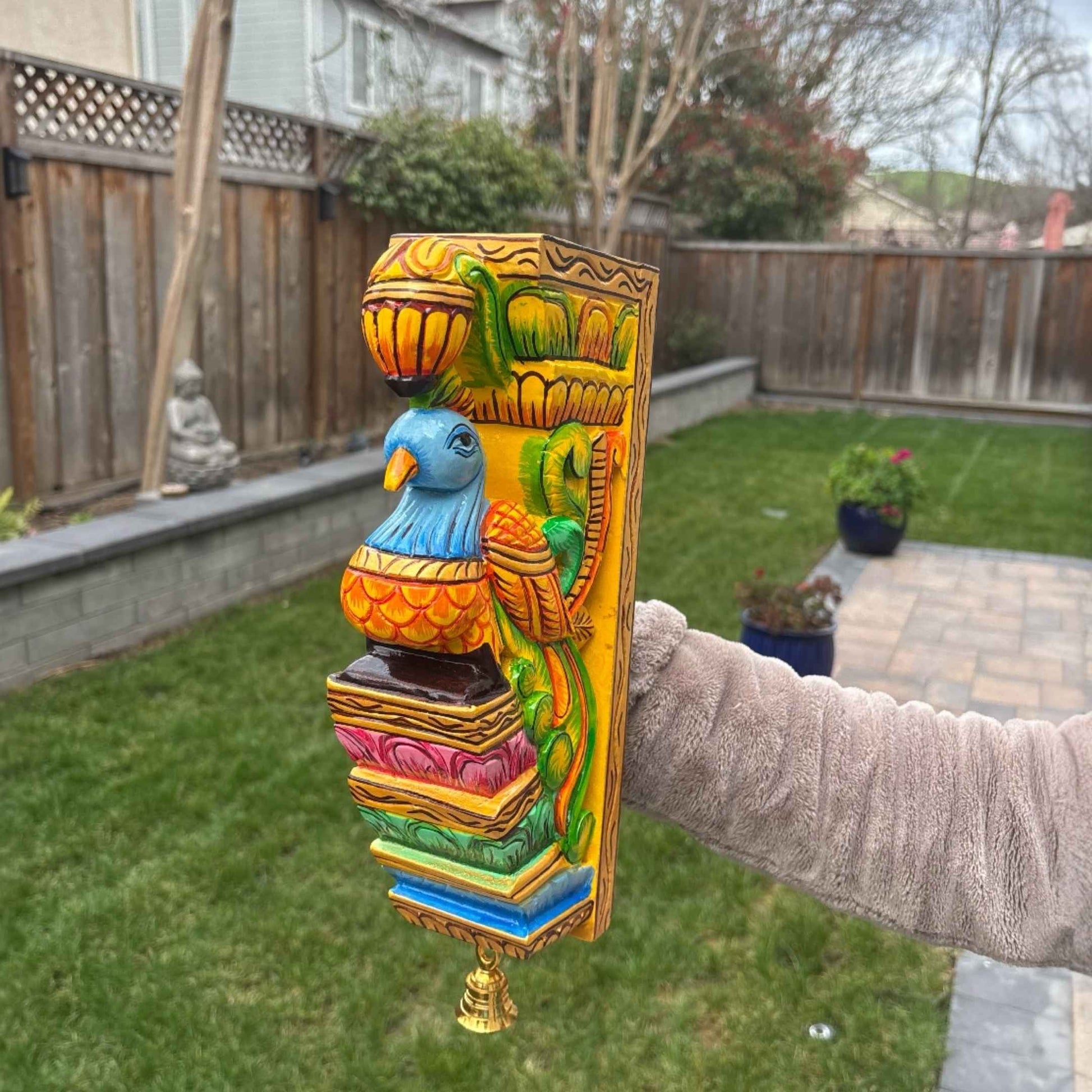 Detailed view of a hand-carved parrot and floral motif on a traditional South Indian wooden wall bracket.